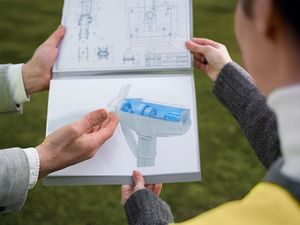 Personen blicken auf Skizze von Windrad